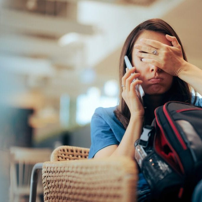 Stressed traveler speaking on her cellphone feeling overwhelmed