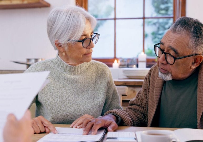 Couple, documents and reading for insurance in retirement, planning and bills or paperwork. Senior people, marriage and communication or discussion for future, saving and finance in kitchen at home